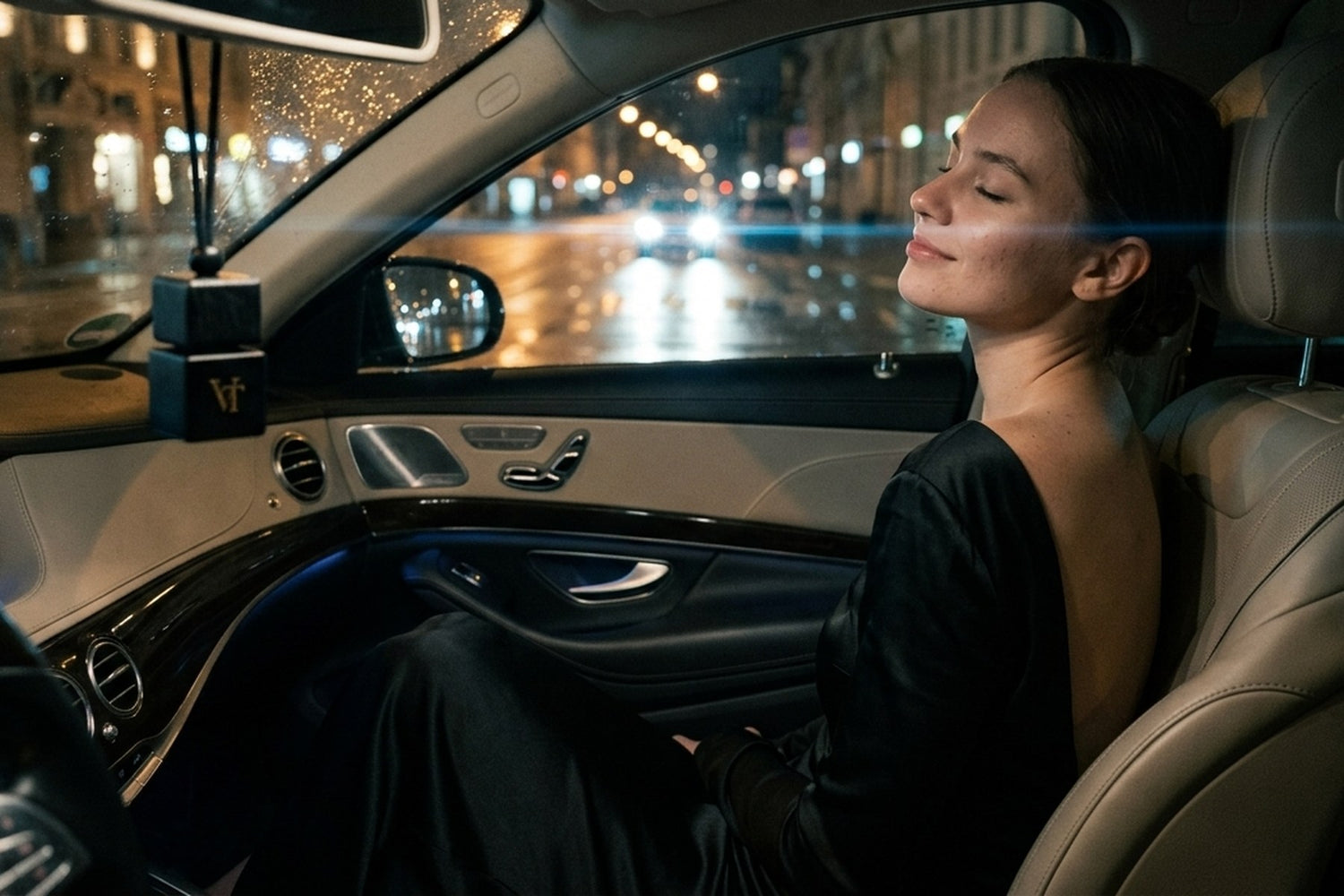 Nachts steigt eine Frau im dunklen Samtkleid aus einem Auto, am Rückspiegel hängt ein VT Flakon.